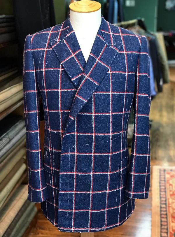 A blue windowpane jacket with a red overcheck on a tailor's stand.