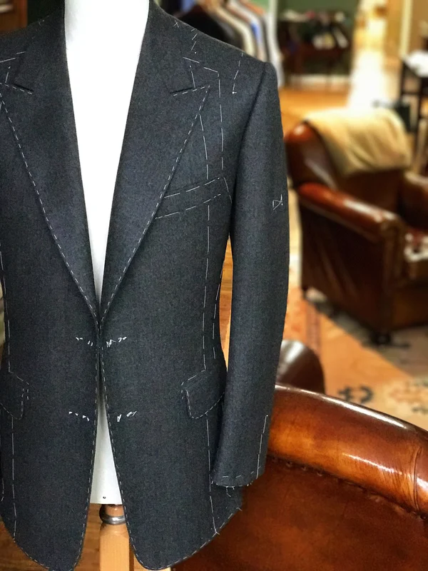 A charcoal chalk-stripe jacket on a stand in the fitting room.