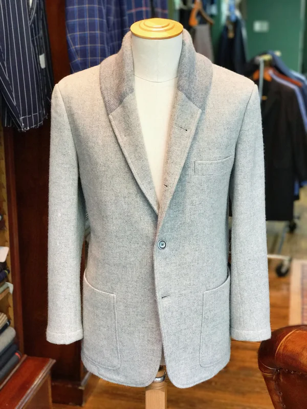 A pale summer jacket with a shawl-style lapel on a stand.